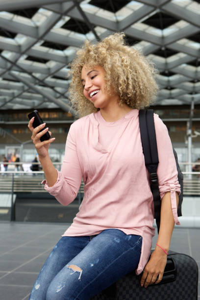 istock Young woman sitting on suitcase with mobile phone 654054984