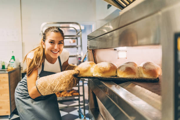istock Beautiful baker removing the hot bread from the oven 654055672
