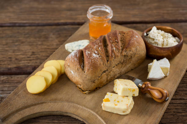 Variety of cheese, brown bread and knife on wooden board