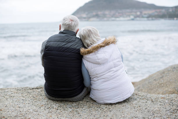 istock Senior couple sitting on rock at beach 654068742