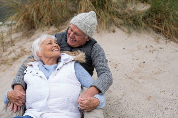 istock Senior couple sitting together on beach 654069488