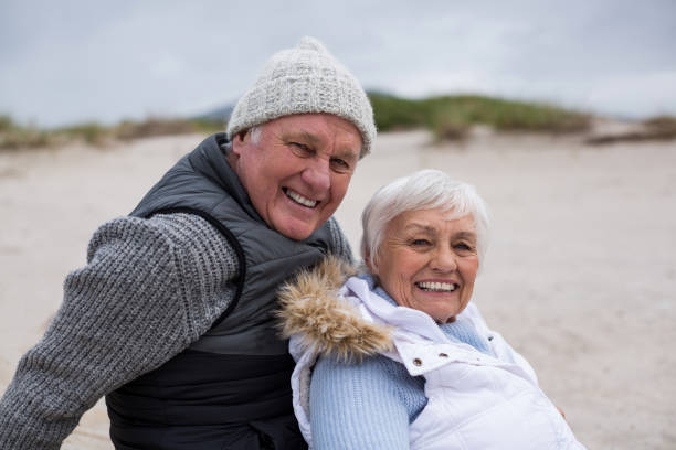 istock Happy senior couple sitting together on beach 654069604