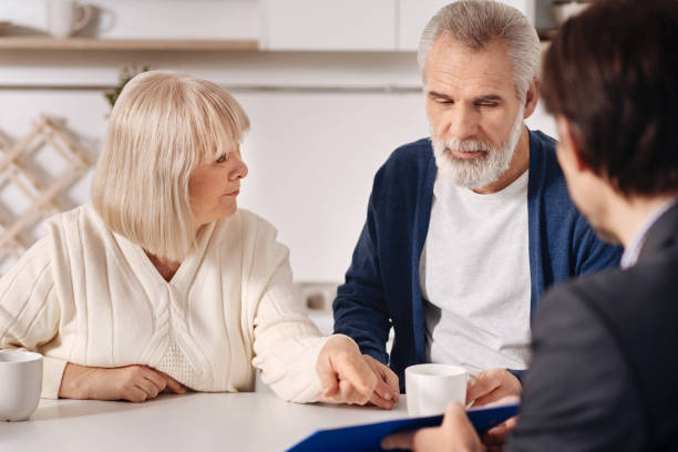 istock Optimistic senior couple having conversation with advisor at home 654079228