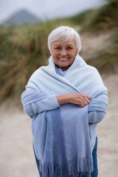 istock Smiling senior woman wrapped in shawl at beach 654079530
