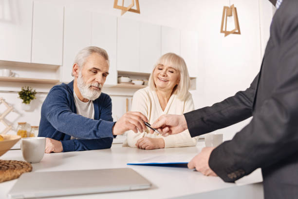 istock Delighted aged couple signing loan contract at home 654082516