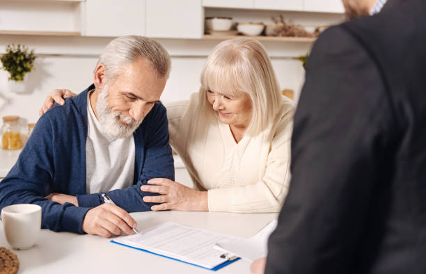 istock Charming cute elderly couple signing documents at home 654082922