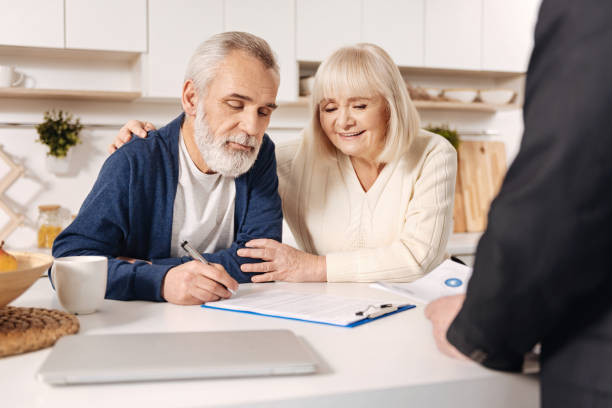 istock Delightful elderly couple signing documents at home 654083004