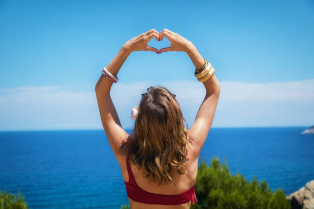 istock Girl holding heart - shape with ocea / sea background. 654083838
