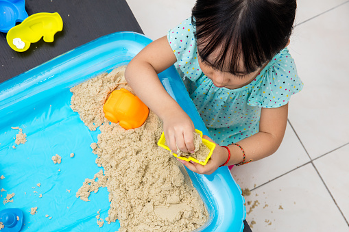 Asian Chinese little girl playing kinetic sand in the living room at home