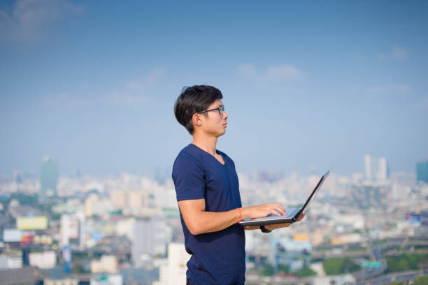 istock Young business man using laptop and digital tablet cityscape background 654095844