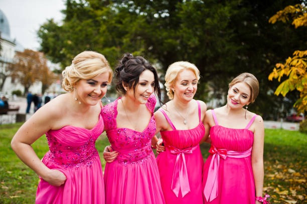 istock Stylish bridesmaids in pink dresses background yellow trees 654095954