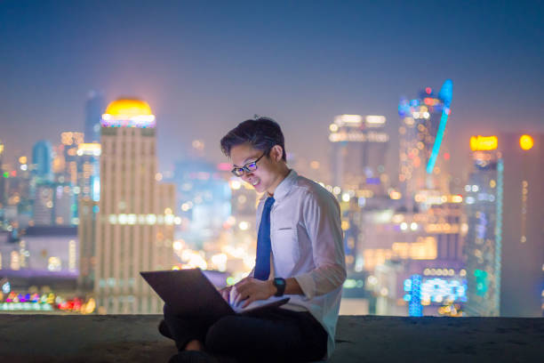 istock Young business man using laptop and digital tablet cityscape background 654100062