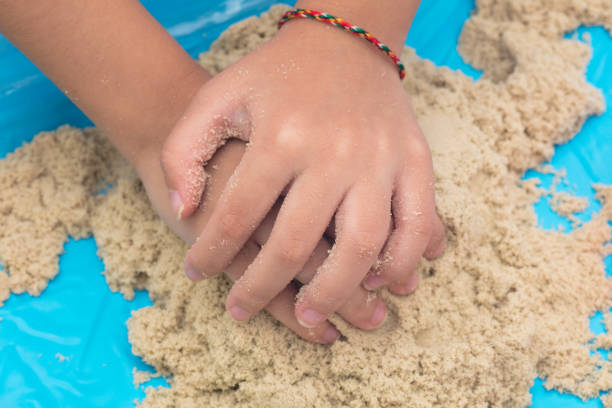 A young boy happily digs and plays with sand, fully immersed in his outdoor adventure on the beach