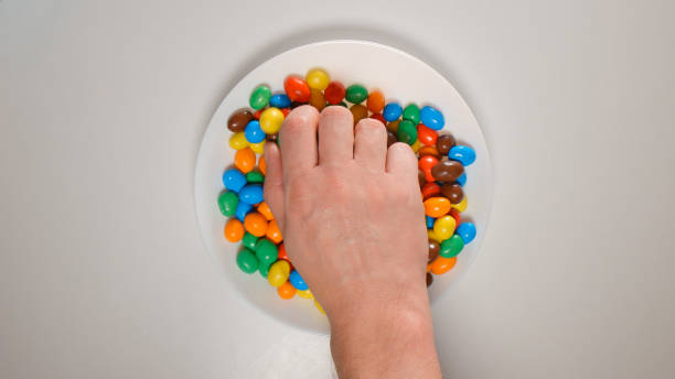 istock TOP VIEW: Human hand takes color candies from a dish 654111500