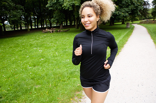 Portrait of young female runner on path in park