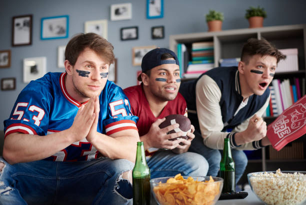 istock Front view of three men watching American football 654142580