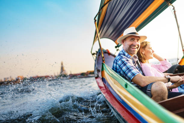 mann mittleren alters und seine gefährtin stattliche blonde dame auf einer bootsfahrt in bangkok - ausflugsboot stock-fotos und bilder