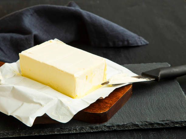 istock Fresh dairy butter piece on wooden cutting board 654152900