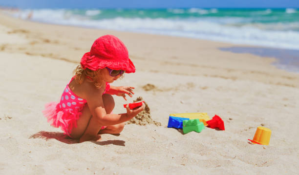 istock cute little girl play with sand on beach 654168480