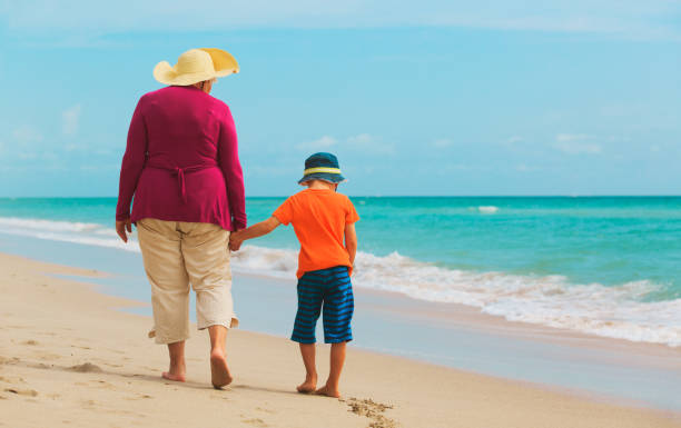 istock Happy grandmother with grandson walk at beach 654168714