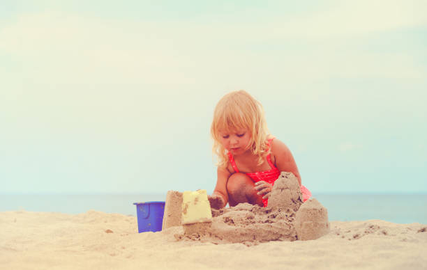 istock cute little girl play with sand on beach 654171388