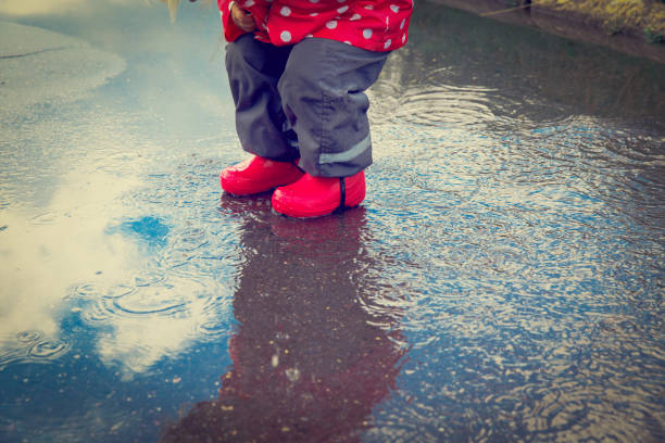 istock little girl play in water puddle 654174556