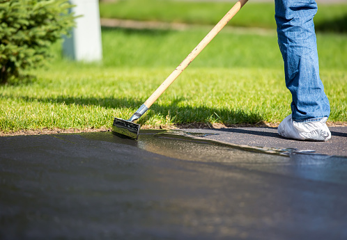 Close-up of a home owner seal coating their driveway. They are using a 
