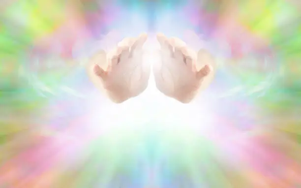 Female hands emerging from vibrant rainbow colored energy field with white light beneath and plenty of copy space