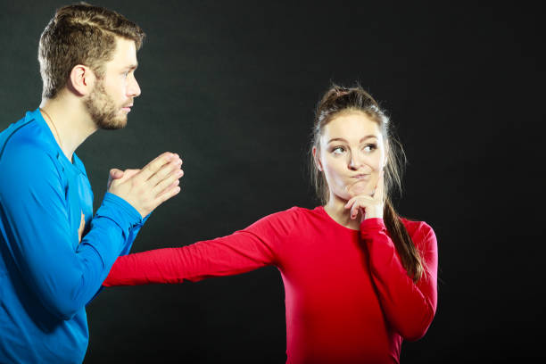 Husband apologizing wife. Man asking woman for forgivness. Boyfriend trying to convince girlfriend. Conflicted couple in studio on black. Relationship problem.