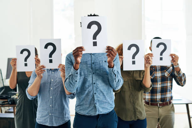 People blocking their faces with a question mark printed on a paper