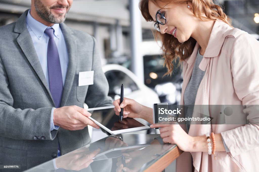 Salesman using digital tablet to sign in Car Dealership Stock Photo