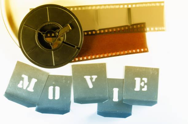 istock Word MOVIE made with metallic stencils. Red yellow film strips and reel. 654207390