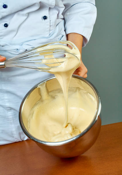 istock chef whips yellow cream in a bowl by hand for making cheesecakes 654220990
