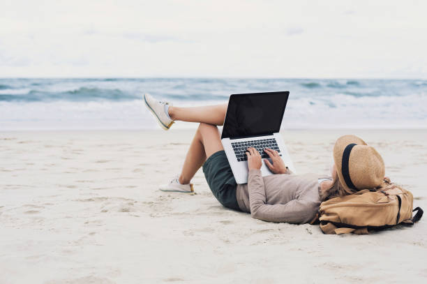 istock Young woman using laptop on a beach 654228620