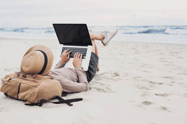 istock Young woman using laptop on a beach 654228650