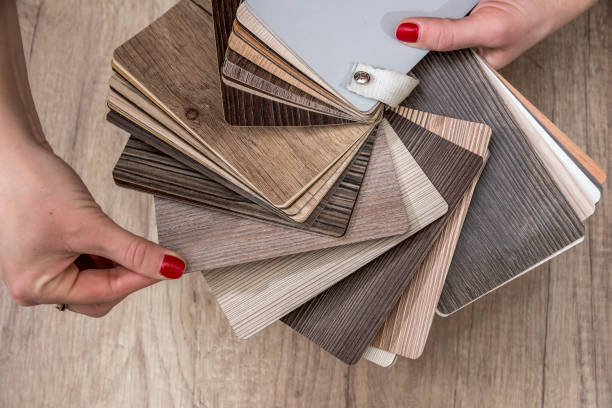 istock women showing Samples of laminate and vinyl floor tile 654232190