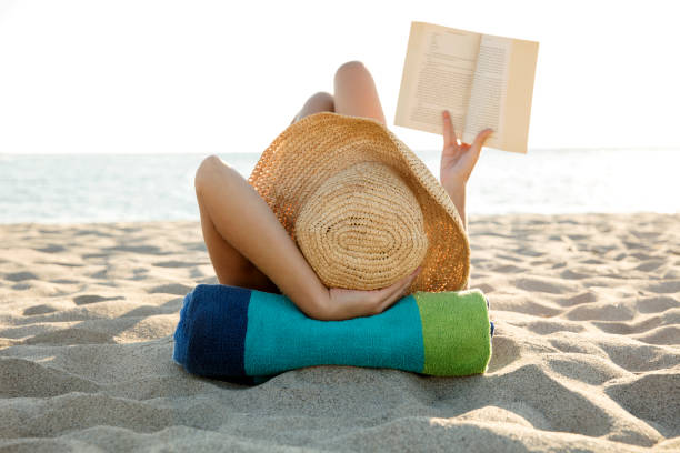 istock Woman lies on the beach reading a book 654239448