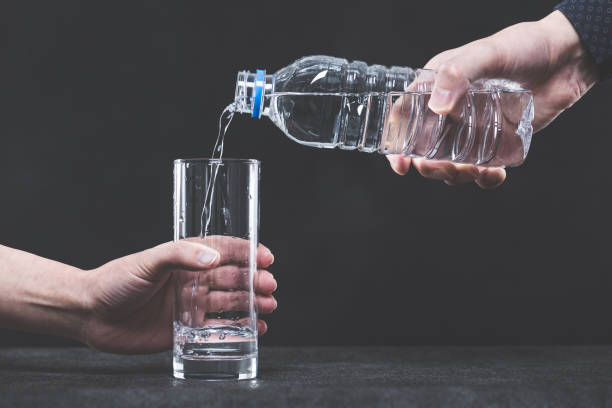 istock Pour water into a glass from a plastic bottle man's hand 654239746