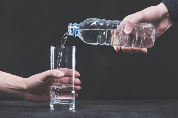 istock Pour water into a glass from a plastic bottle man's hand 654239750