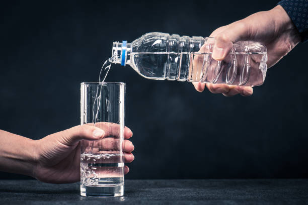 istock Pour water into a glass from a plastic bottle man's hand 654239758