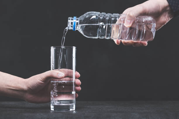 istock Pour water into a glass from a plastic bottle man's hand 654239762