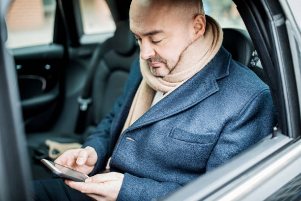 istock Mature businessman sitting in car using mobile phone 654245140