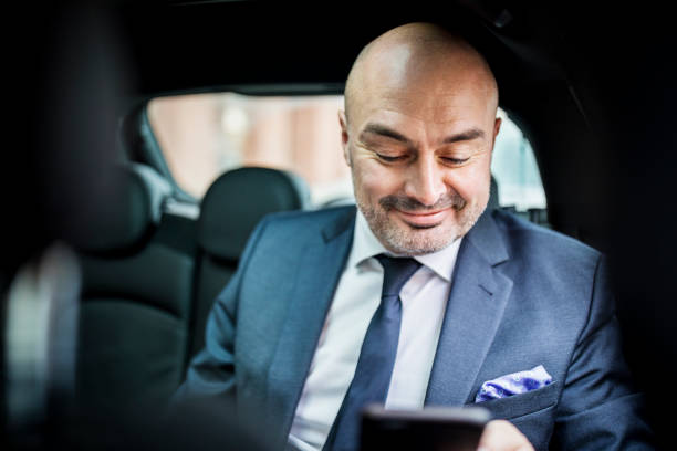 istock Mature businessman using mobile phone while traveling by car 654245284