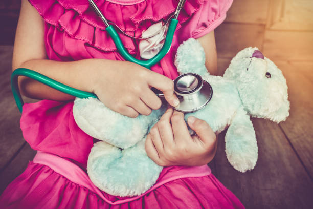 istock Child playing doctor with plush toy bear. Vintage tone effect. 654245352