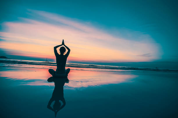 istock Silhouette young woman practicing yoga on the beach at sunset. 654259094