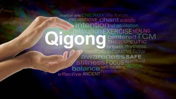 Female cupped hands with the word QIGONG between surrounded by word cloud on a multicolored light centered dark background