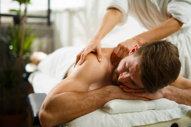 mann mit rückenmassage im wellnessbereich. - massieren stock-fotos und bilder