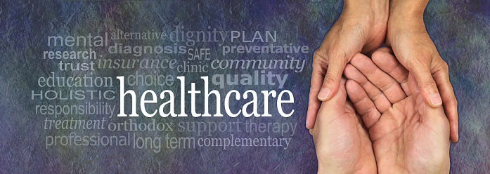 Female hands gently cradling male hands on a rustic dark stone background with a healthcare word cloud to the left