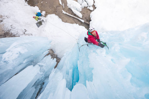 escalada na icicle vertical usando o piolet no gelo homem - ice axe - fotografias e filmes do acervo