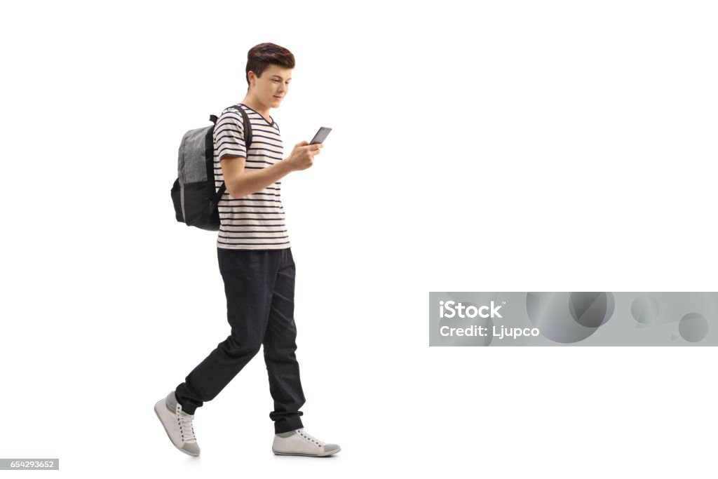 Estudiante adolescente caminando y mirando un teléfono - Foto de stock de Adolescente libre de derechos